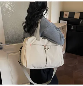 Dettaglio della borsa da viaggio in tela beige con tracolla e cerniera decorativa 'A'