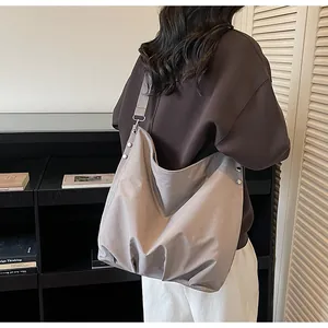 Detailweergave van de grote grijze hobo tas met metalen klinknagels en brede schouderriem