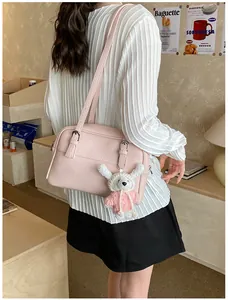 Detail of pink lychee texture shoulder bag with cute white rabbit plush keychain accessory