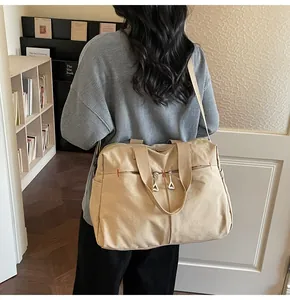 Dettaglio della borsa da viaggio in tela kaki con cuciture rosse e doppie tasche zip