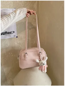 Detailed view of pink lychee texture leather bag with a cute white bunny pendant