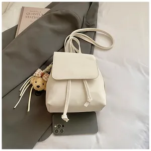 Detailed view of white faux leather backpack with metallic buckle and cute bear charm