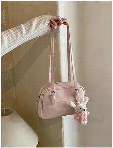 Detail of pink lychee textured leather shoulder bag with a cute plush bunny charm