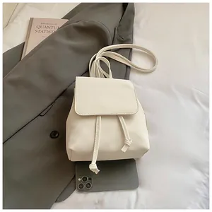Mini white PU leather backpack with flap drawstring detail and smartphone for scale