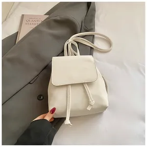 Detail of a white faux leather mini backpack with drawstring closure and flap design