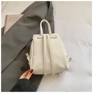 Top view of cream white leather backpack with silver eyelet drawstrings and top handle