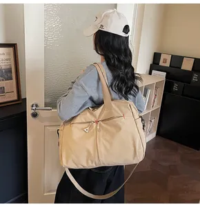 Dettaglio borsa da viaggio in tela beige con tasca a zip e tracolla regolabile resistente