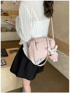 Detail view of pink lychee textured leather crossbody bag with cute bunny pendant charm
