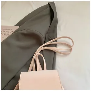 Close-up of a pale pink leather handbag with multi-strap design on a suit jacket