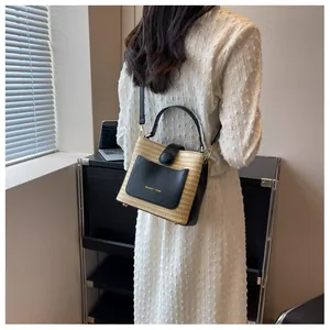 Detail of straw woven bucket bag with leather handles and gold metal hardware accents
