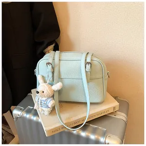 Detail of light blue lychee pattern leather handbag with cute white rabbit charm