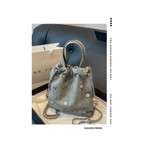 Détail du sac seau en denim gris avec rivets en cœur et bandoulière chaîne