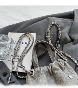 Détail du sac seau en tissu gris avec bandoulière chaîne et pendentif coeur argenté