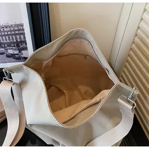 Detailopname van de ruime binnenvoering en het ritsvak van deze grote beige draagtas