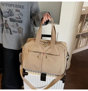 Grande borsa da viaggio in tela beige posta su una valigia bianca in un ambiente di vita