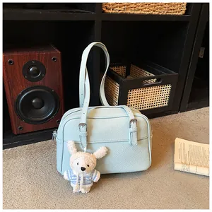 Detail of light blue lychee pattern crossbody bag with a plush bunny charm and silver buckles