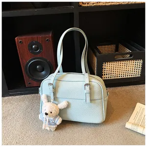 Close-up of light blue litchi pattern bag with silver zipper and plush rabbit charm