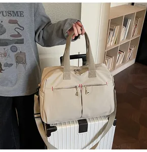 Dettaglio borsa da viaggio in tela con cuciture rosse e manici rinforzati su valigia