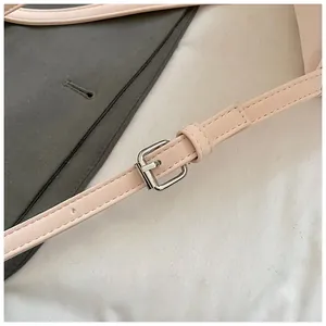 Detailed close-up of light pink leather shoulder strap with polished silver metal buckle