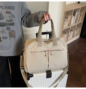 Dettaglio borsa da viaggio in tela beige con tasche con zip e tracolla su valigia