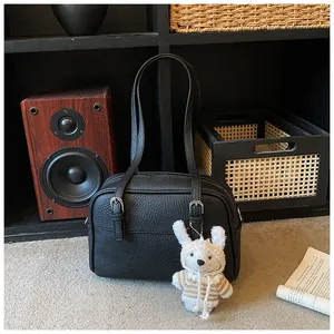 Detailed close-up of a black lychee texture leather shoulder bag with a cute rabbit charm