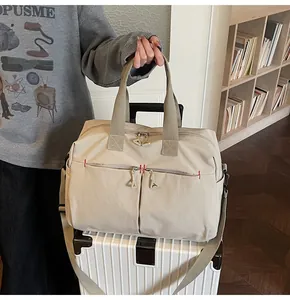 Dettaglio borsa da viaggio in tela con fascia trolley e cuciture rosse sulle tasche