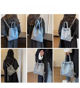 Mannequin portant un sac seau en jean bleu clair avec rivets argentés et chaîne en métal