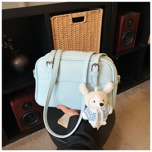 Detail of light blue lychee pattern bag with a cute bear charm in a cozy indoor setting
