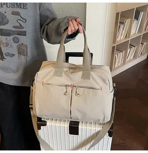 Dettaglio borsa da viaggio kaki con ampie cinghie e tasche posizionata su una valigia