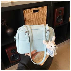 Detail of light blue lychee pattern crossbody bag with a cute white teddy bear charm