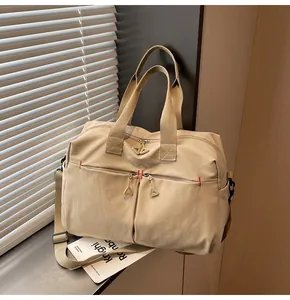 Dettaglio della borsa da viaggio in tela con cerniere a triangolo e cuciture rosse a contrasto