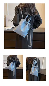Détail du sac seau en denim bleu clair avec clous argentés et cordon de serrage chaîne