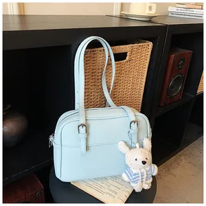 Detail of light blue lychee pattern leather handbag with cute teddy bear charm