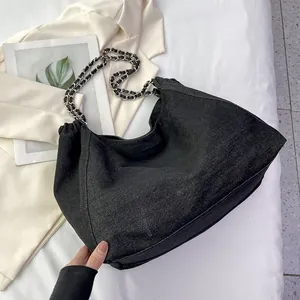 Close-up of black denim tote bag with silver chain strap and slouchy design detail