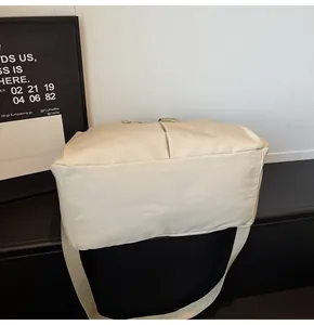 Dettaglio della borsa da viaggio in tela crema con ampia tracolla in stile minimalista