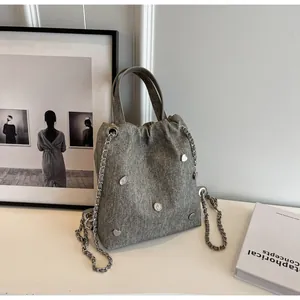 Détail du sac seau gris en denim avec breloques cœur argentées et bandoulière chaîne