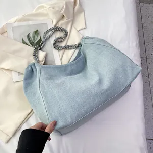 Close-up of light blue denim hobo bag with vintage metal chain and pleated fabric detail
