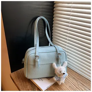 Detail of light blue lychee pattern leather bag with a cute plush charm and silver lake book