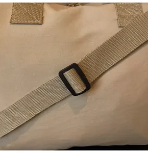 Dettaglio del tessuto in tela kaki e della fibbia nera regolabile sulla borsa da viaggio