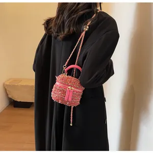 Detailansicht der rosa Tweed-Mini-Eimertasche mit Lederriemen auf einem schwarzen Mantel