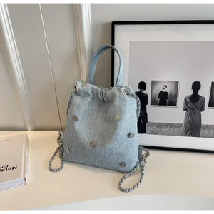 Détail du mini sac en denim bleu clair avec cordon et ornements en métal argenté en cœur