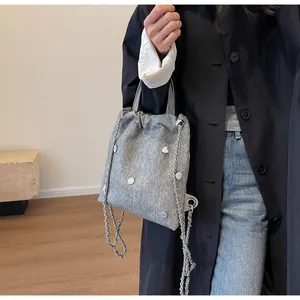 Détail du sac en tissu texturé gris avec chaîne argentée et bouton en métal en forme de cœur