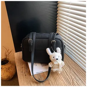 Detail of black lychee grain leather handbag with a cute knitted rabbit charm on it