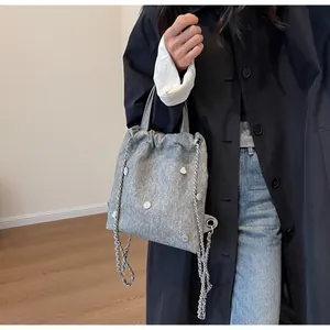 Détail du sac gris texturé à cordon avec boucles cœur argentées et chaîne