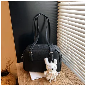 Detail of black lychee grain leather handbag with silver buckles and plush rabbit charm