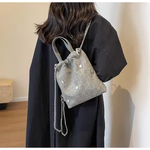 Détail du sac bandoulière en tissu gris avec breloques cœur et bandoulière en chaîne