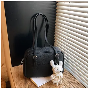 Detail shot of black litchi texture crossbody bag with cute white bunny charm decoration