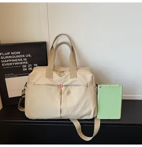 Dettaglio della borsa da viaggio in tela beige con grande capacità e cuciture rosse rinforzate