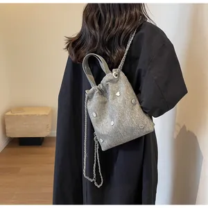 Détail du sac seau en tissu gris avec clous en forme de cœur et bandoulière chaîne