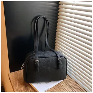 Detail of black lychee grain leather handbag with vertical straps and metal buckles